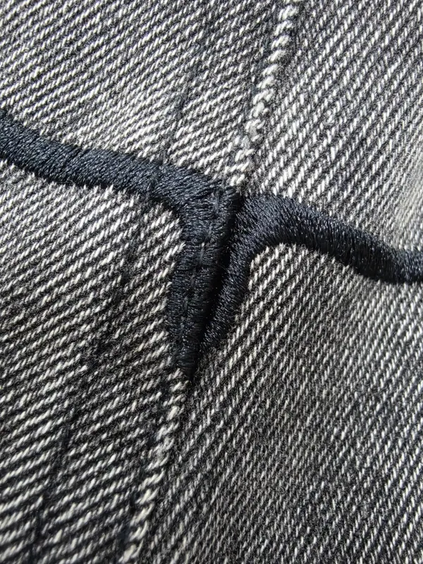 Black stitched artwork on a grey denim sample