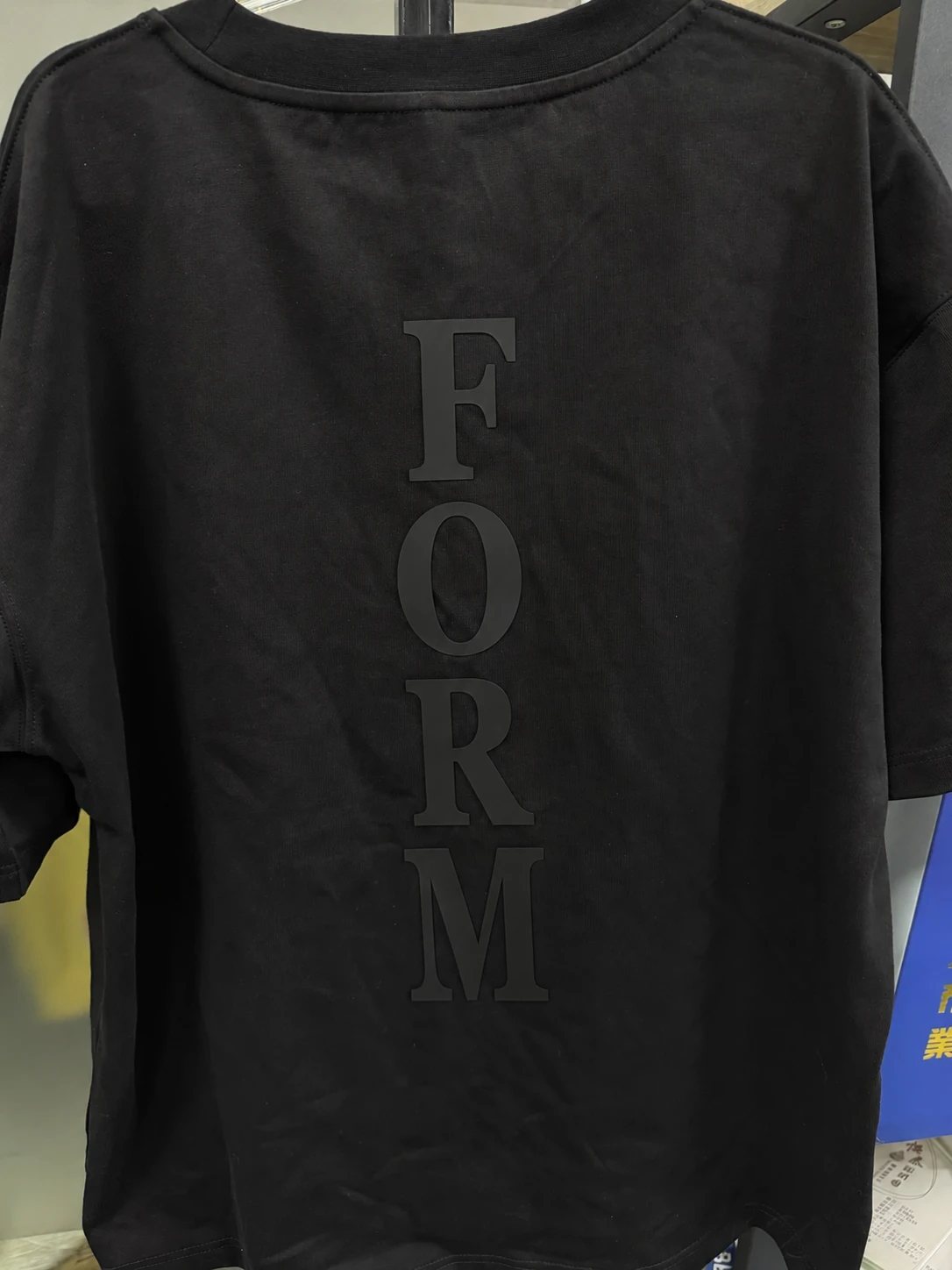 Back view of a black T-shirt with vertical FORM silicone lettering