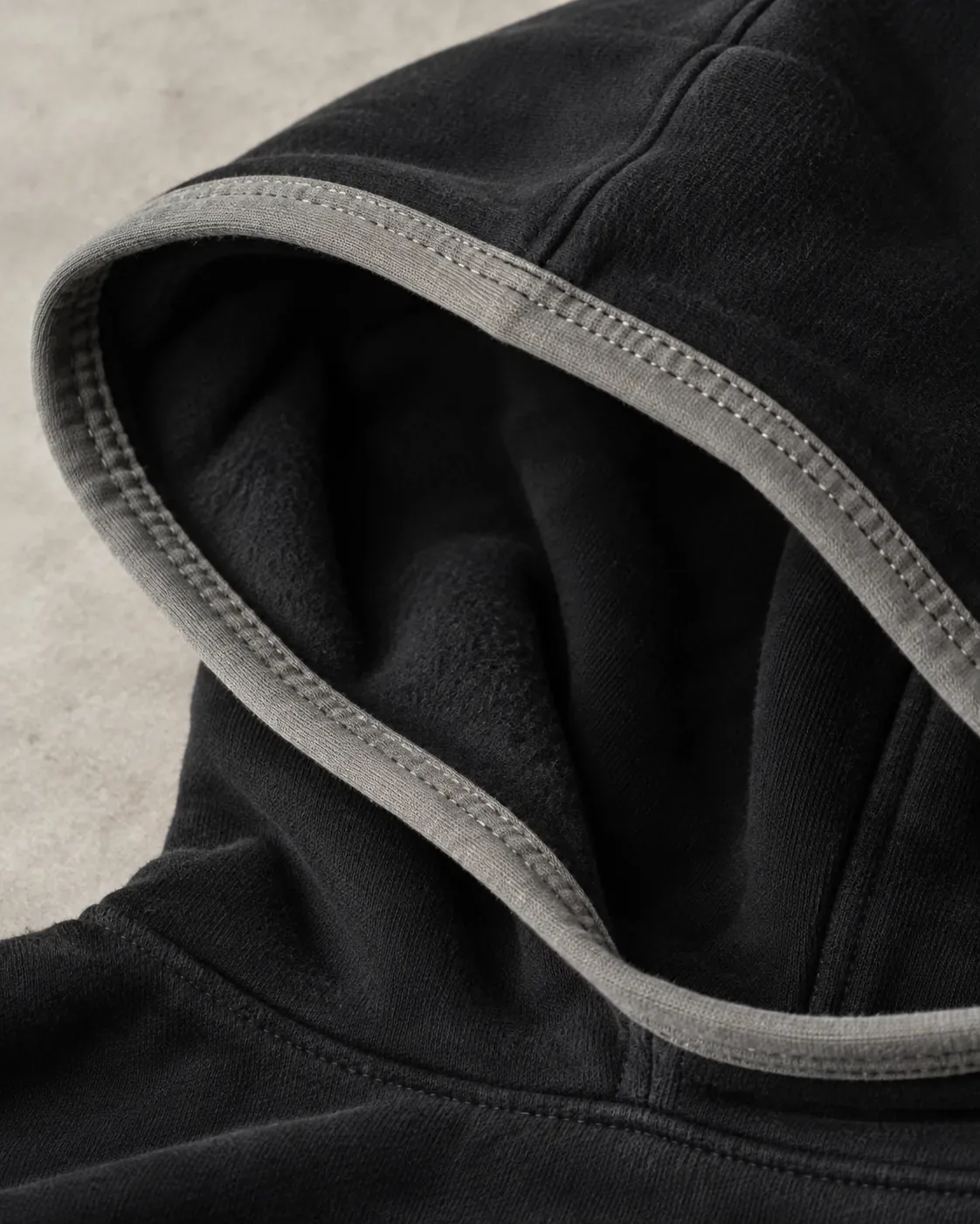 Contrast binding on the hood edge of a black fleece hoodie