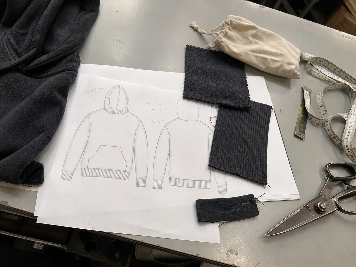Reference garments, sketches and fabric swatches laid out for a brief