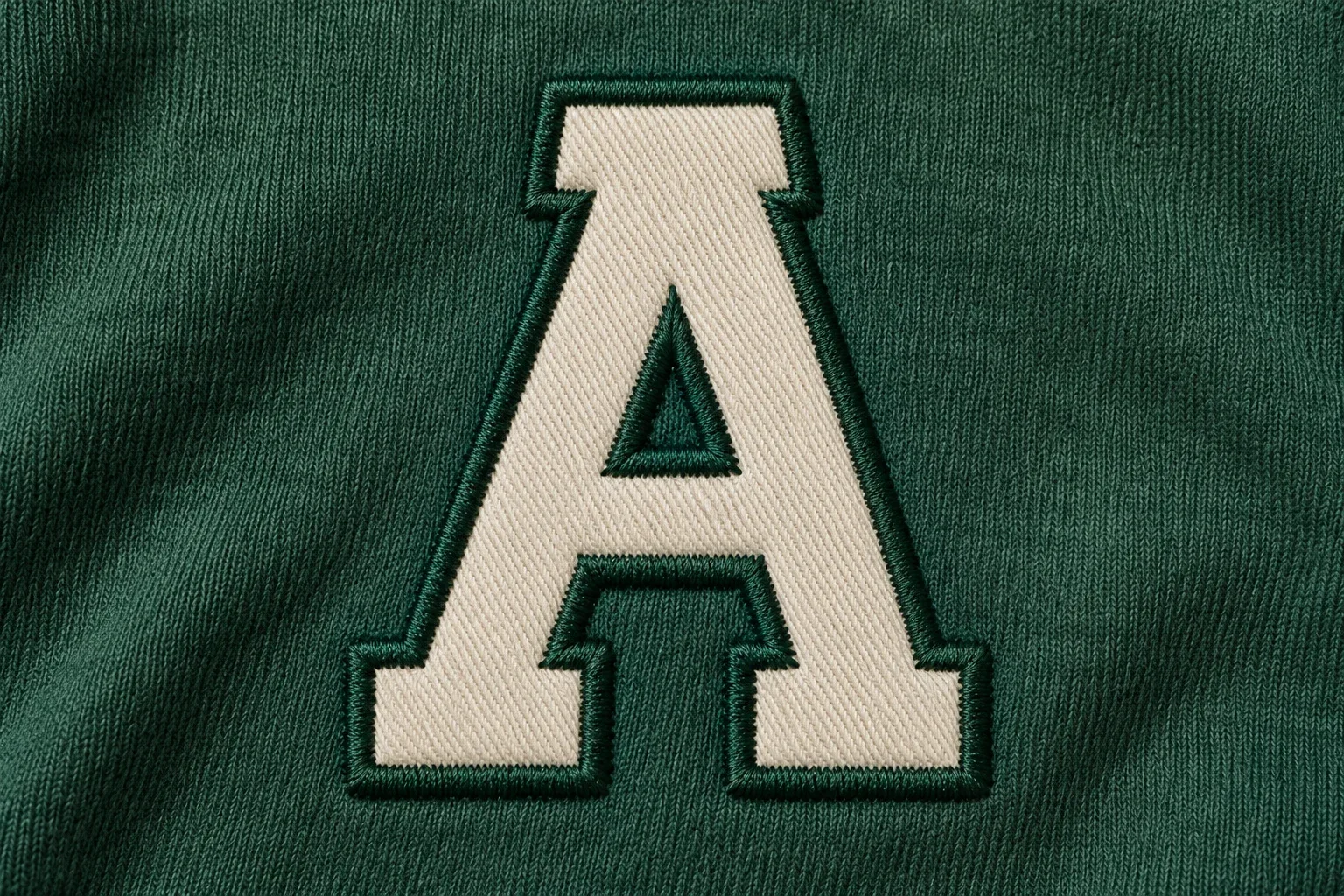 Cream twill letter with a neat dark green stitched border covering the cut edge