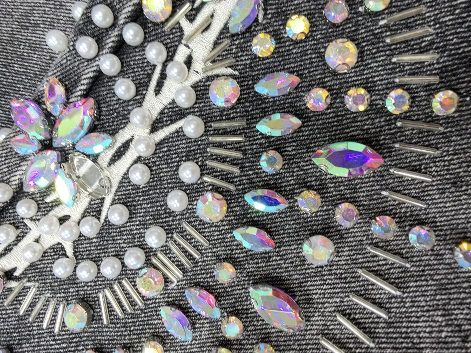 Close-up of hand-set stones, beads and stitching on washed denim